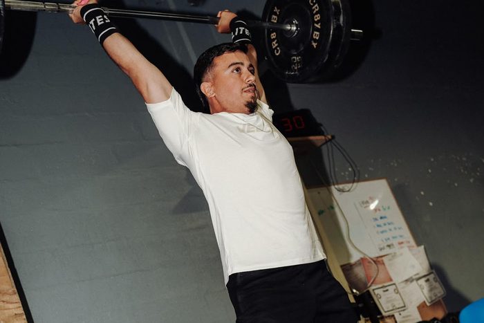 Danny pressing a loaded barbell overhead in the gym