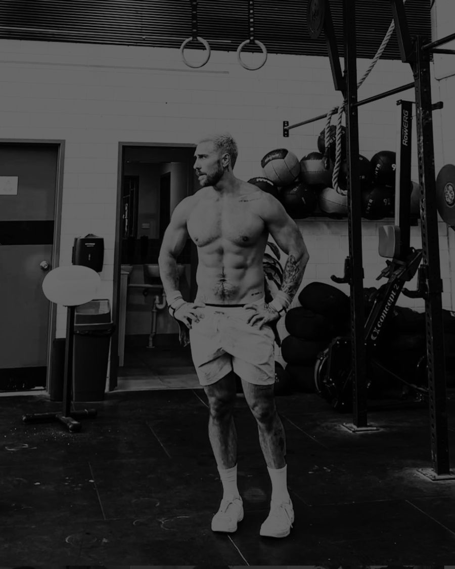Athlete standing in a gym between training sets, photographed in black and white