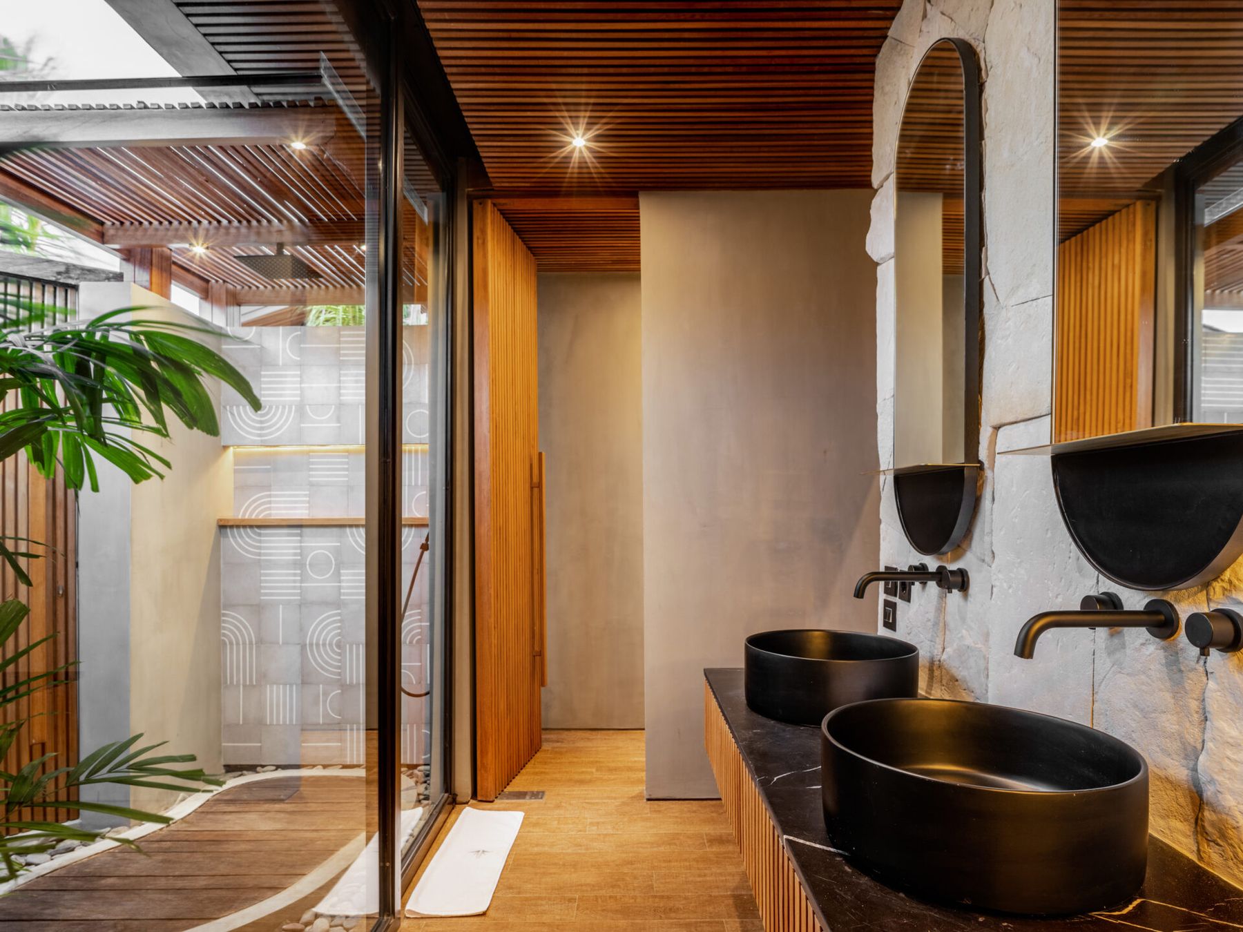 Stone bathroom with double black basins and tropical planting