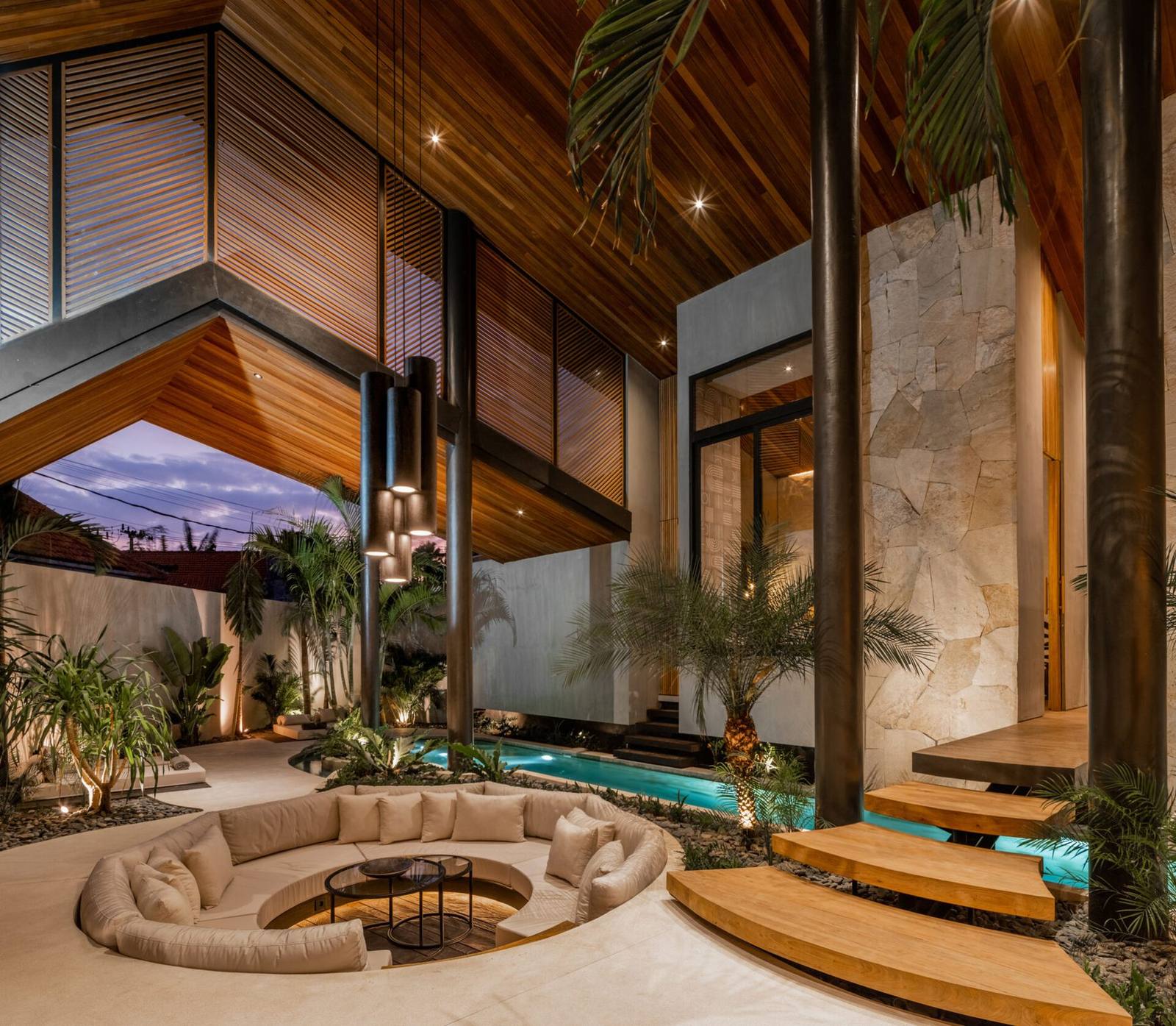 Sunken firepit lounge glowing at dusk under a vaulted villa roof