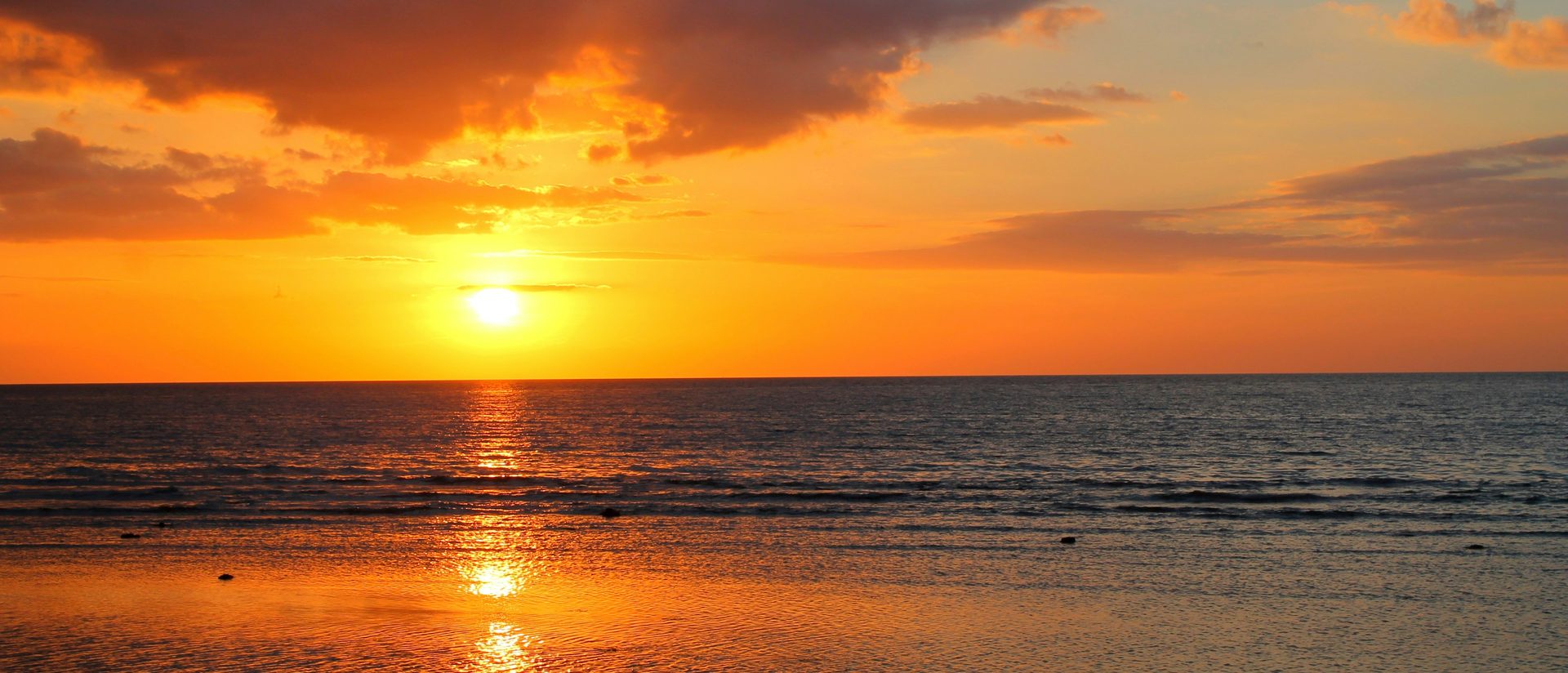 Sun setting over the sea off Bali, orange sky and calm water
