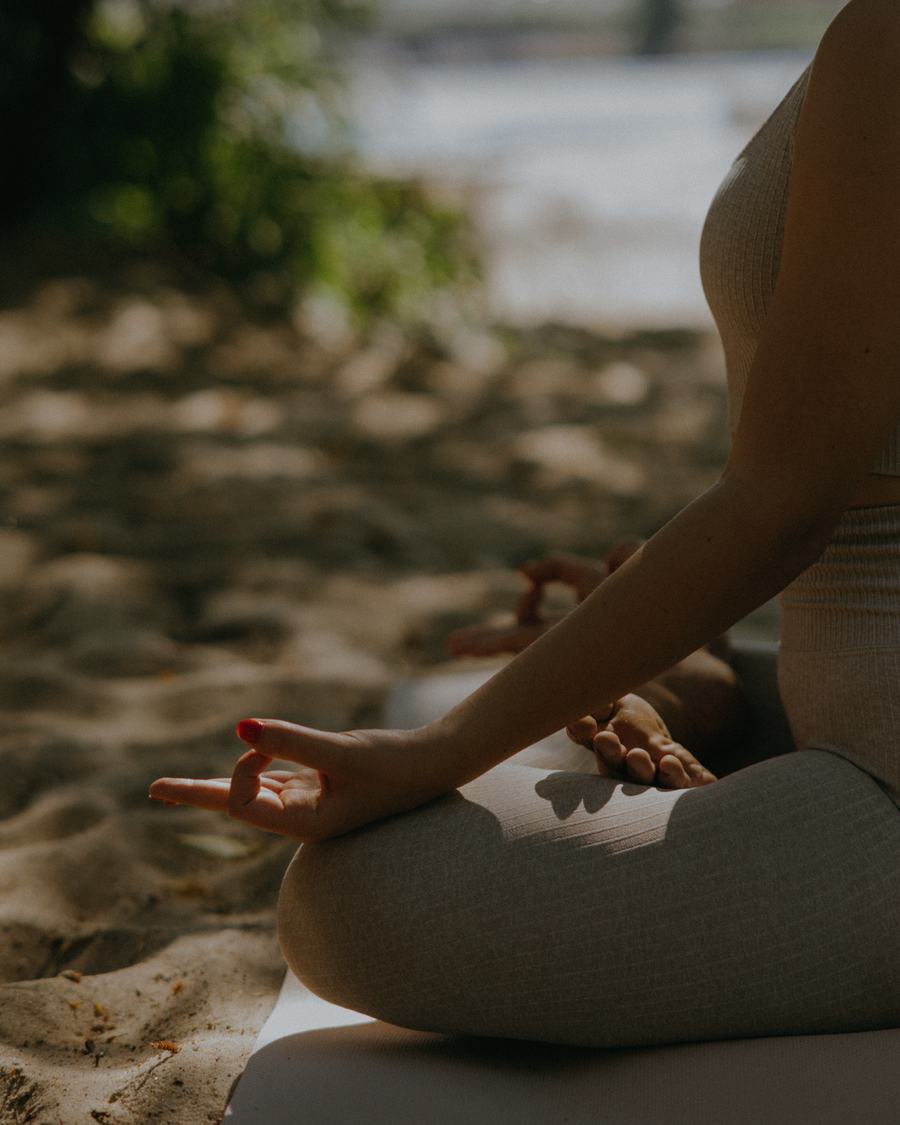 Woman sitting cross-legged on the sand in quiet reflection