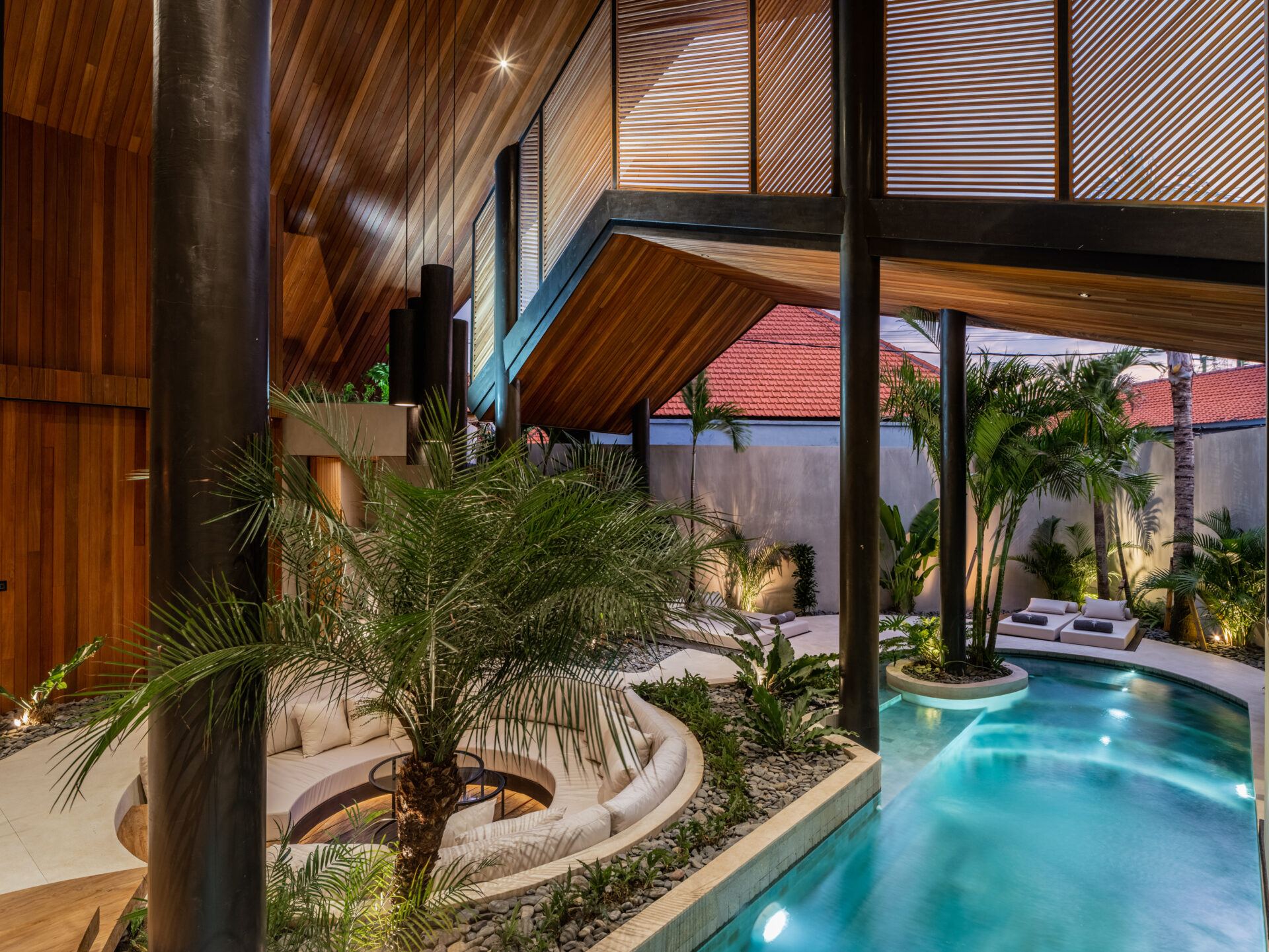 Private villa pool curving around a palm island under a tropical sky in Bali