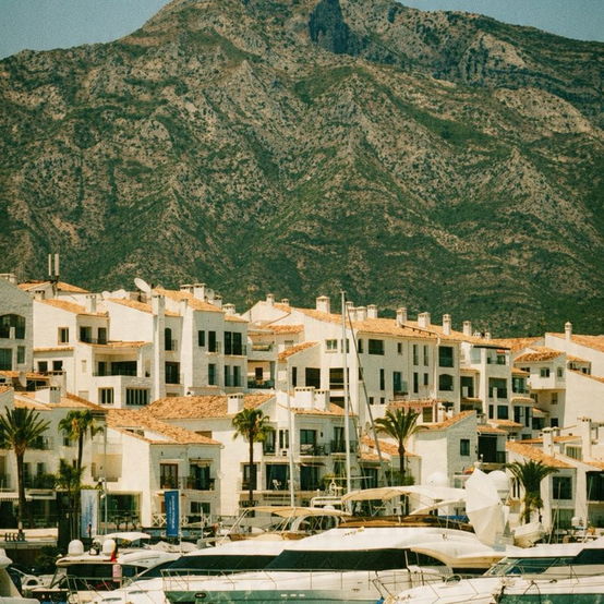 White coastal town beneath a mountain ridge