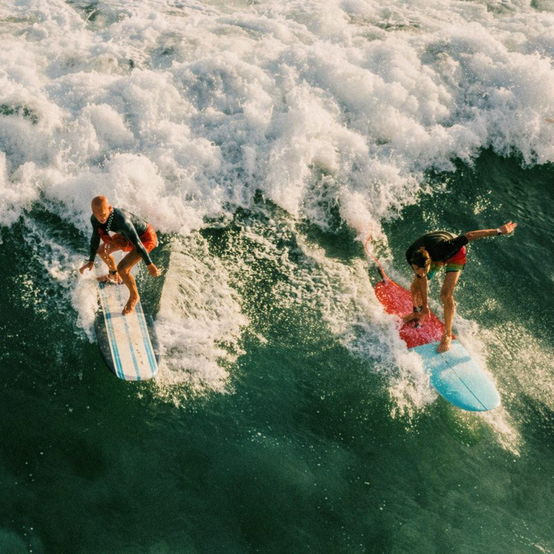 Two surfers dropping into the same wave
