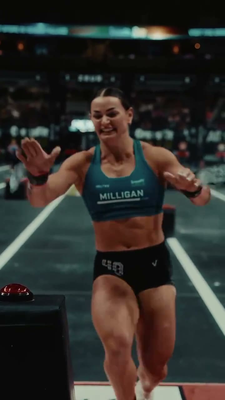 Kyra Milligan running across a CrossFit Games floor, smiling, MILLIGAN on her top