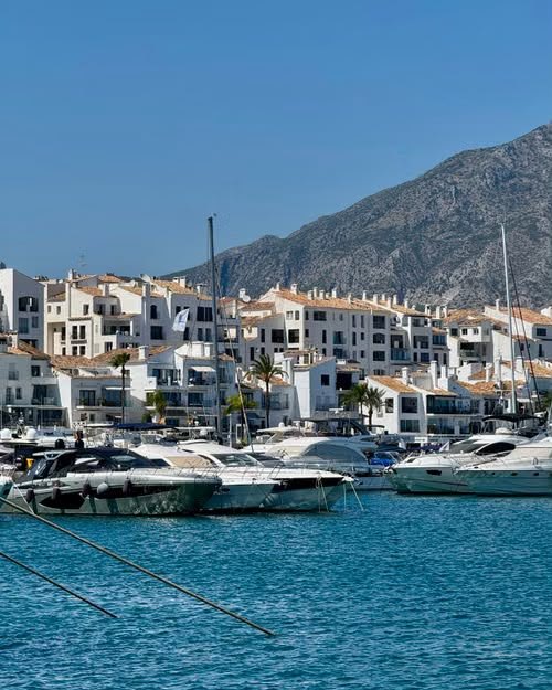 White apartments and yachts in Puerto Banús marina, Marbella, with the mountains behind