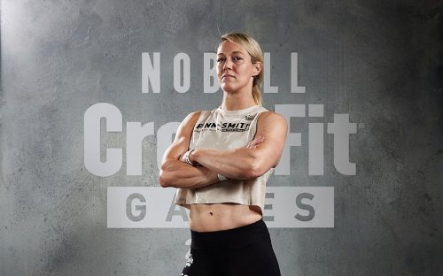 Vicki, arms folded, in front of a CrossFit Games backdrop