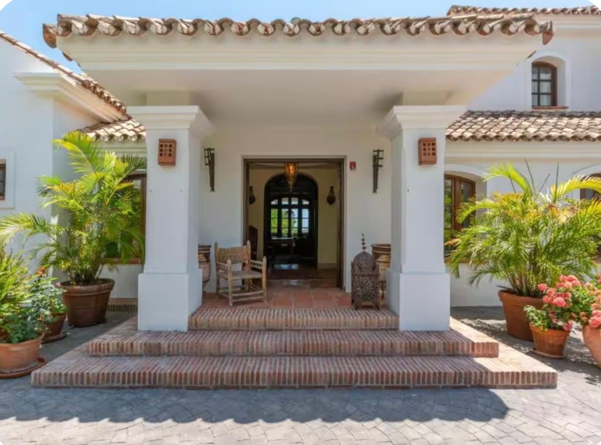 Villa entrance with columned porch, terracotta steps and potted palms