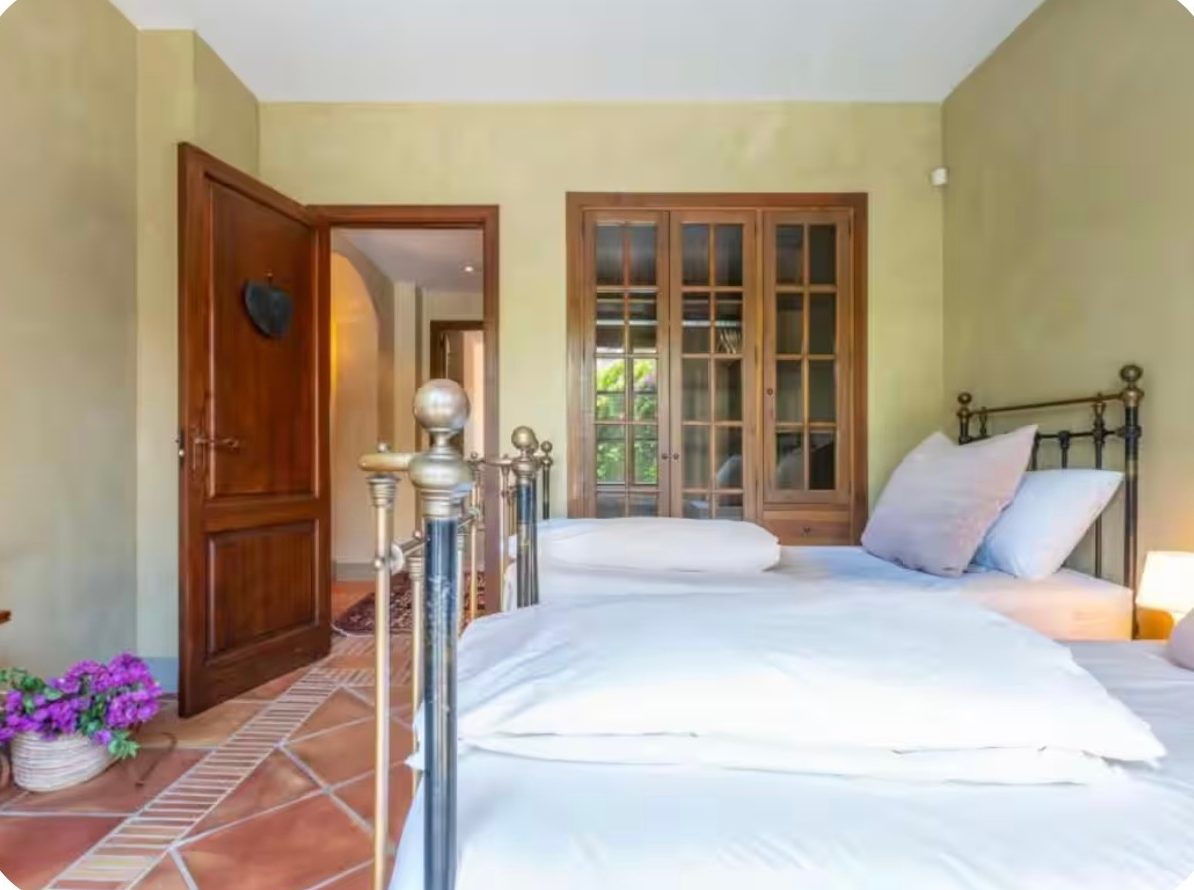 Twin bedroom with brass beds and garden views